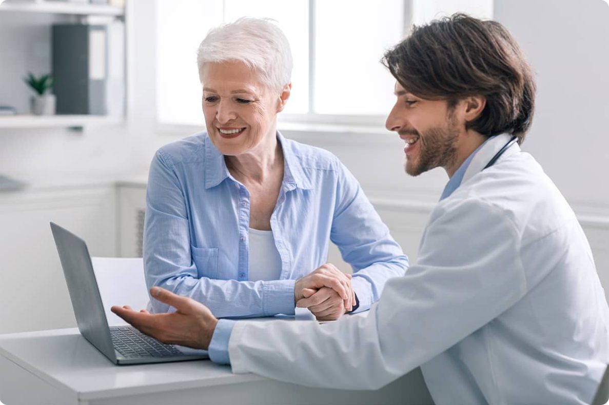 A doctor showing a senior patient information on a laptop
